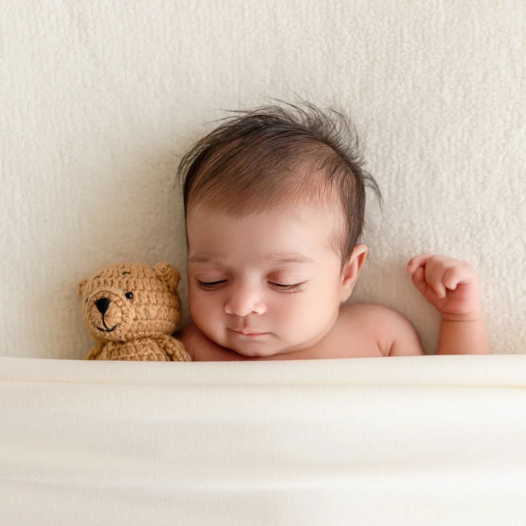 Baby photographers frame baby in sleep holding mini teddy
